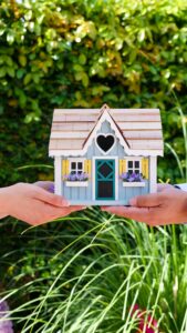 pexels photo 7578931 7578931 Two hands hold a colorful miniature house outdoors, symbolizing real estate and home ownership.