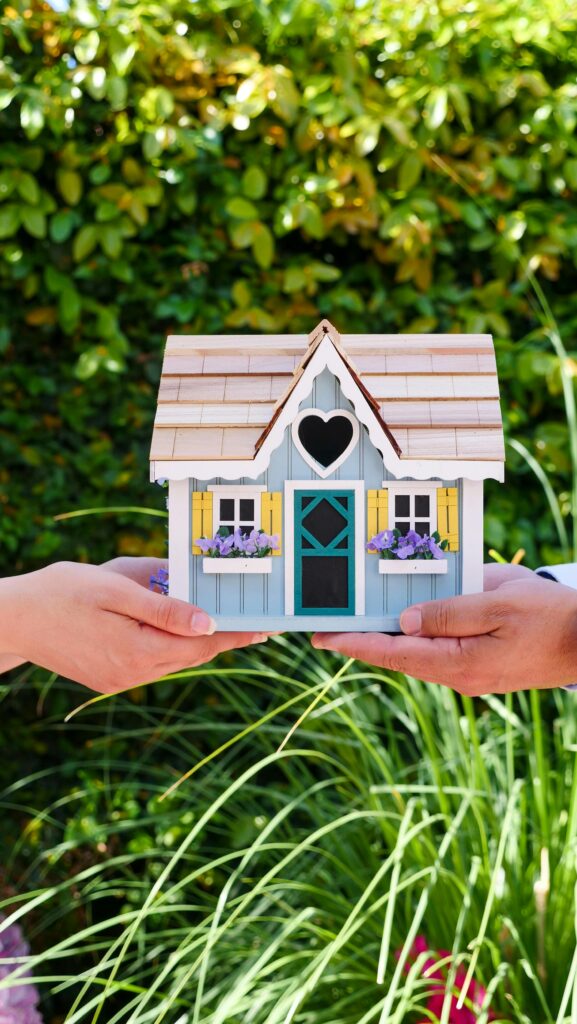 pexels photo 7578931 7578931 Two hands hold a colorful miniature house outdoors, symbolizing real estate and home ownership.